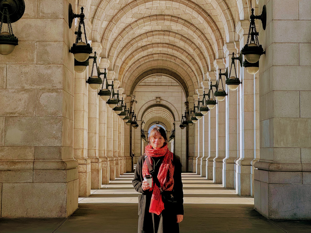 Architect Karin Gunnerek standing in a sunlit stone archway.